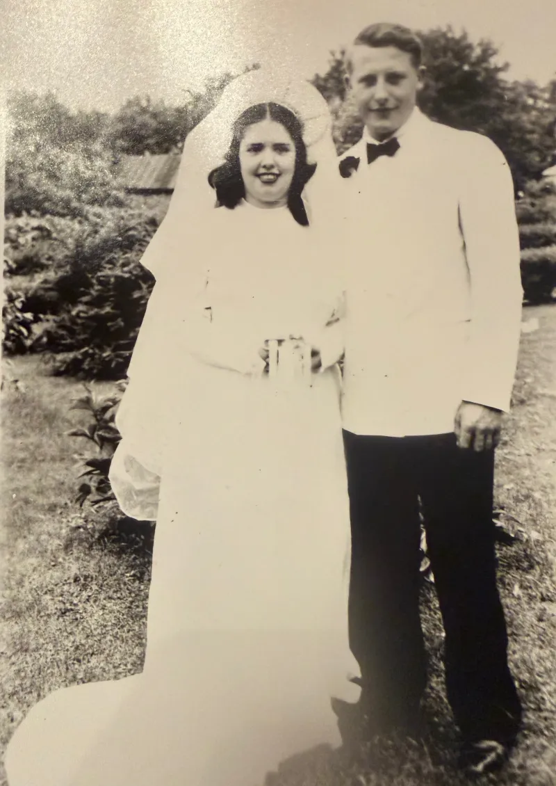 A newlywed couple outdoors in their Sunday best